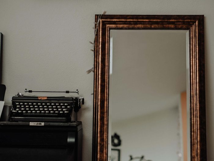 Typewriter and mirror leaning against wall 