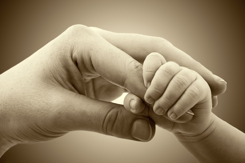 Baby's hand grasping mother's hand