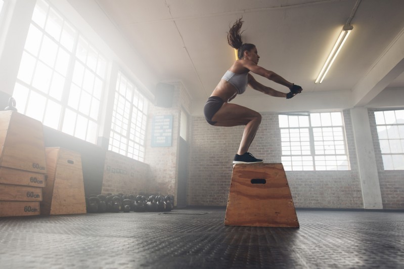 A woman demonstrating an agile approach by jumping onto a box
