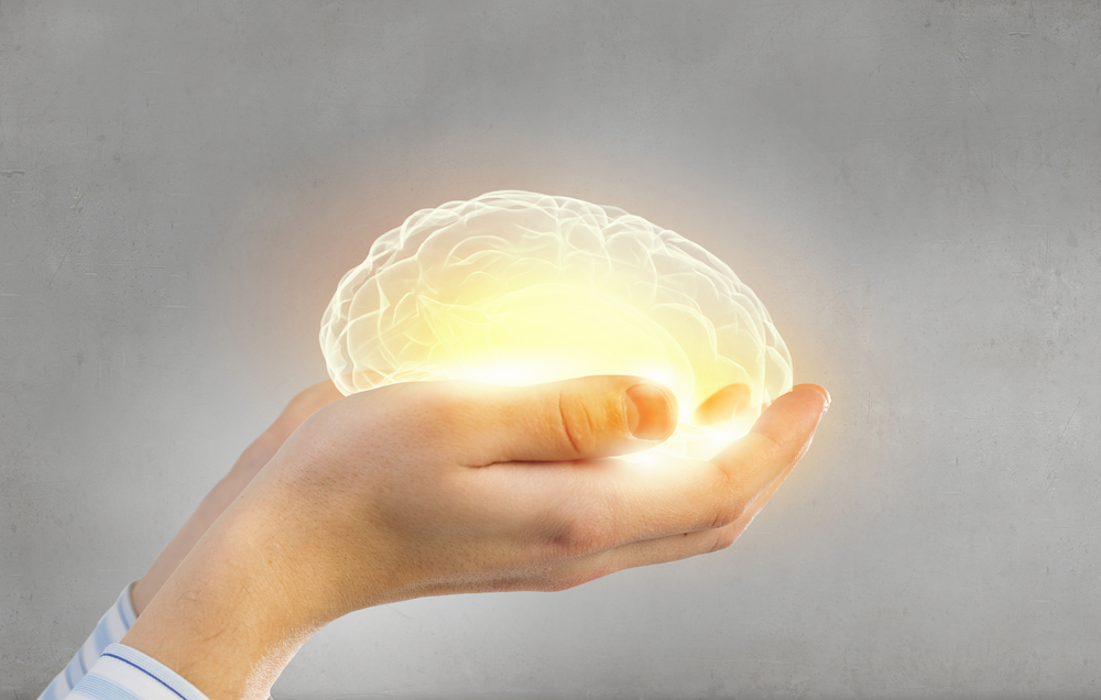 hands holding warm glowing brain representing mental health care to to help relearn mental health