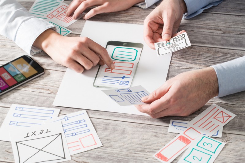 Hands arranging a paper version of the learner journey according to heuristic evaluation principles