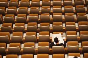 person sitting alone in auditorium, representing opposite of social learning