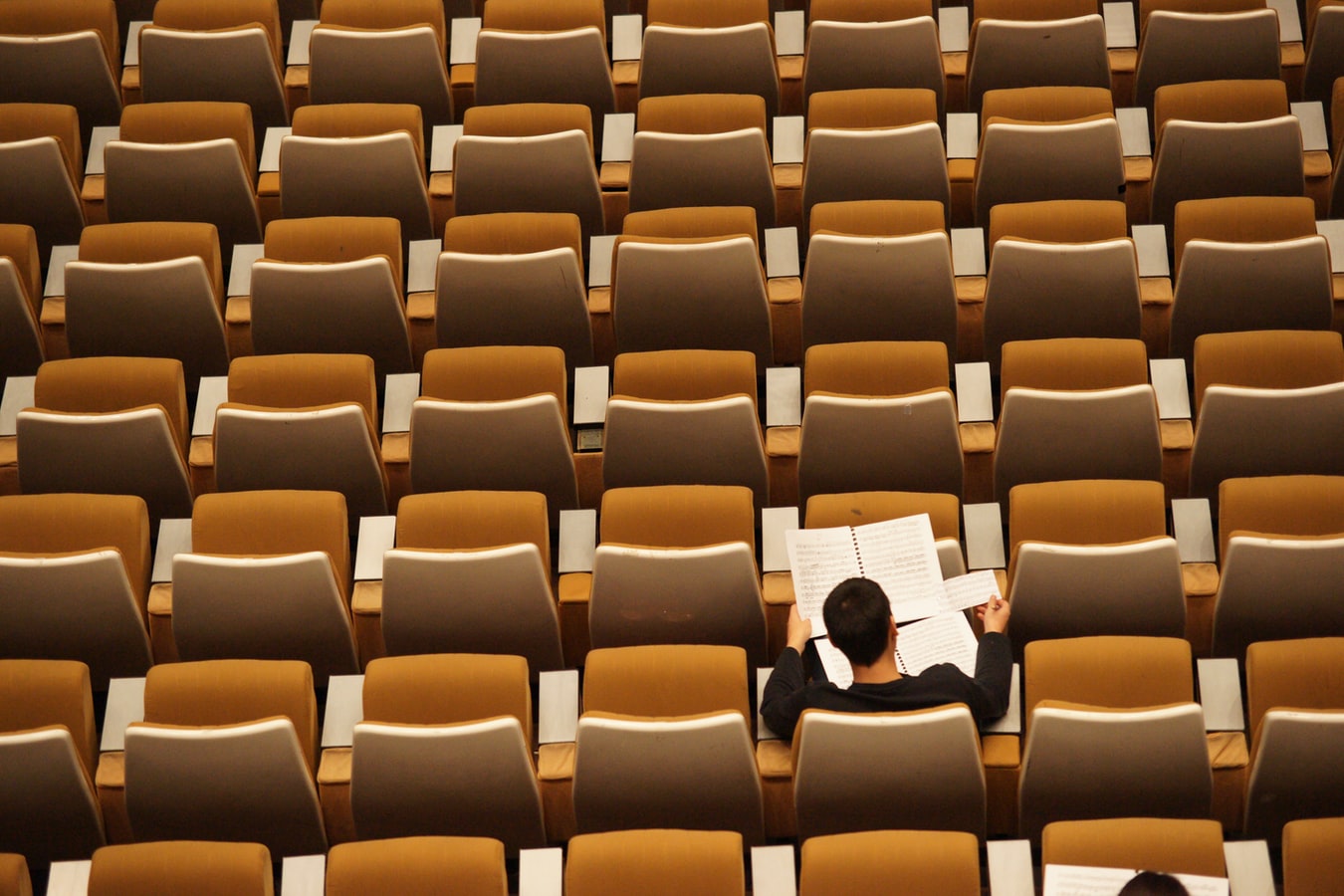 person sitting alone in auditorium, representing opposite of social learning