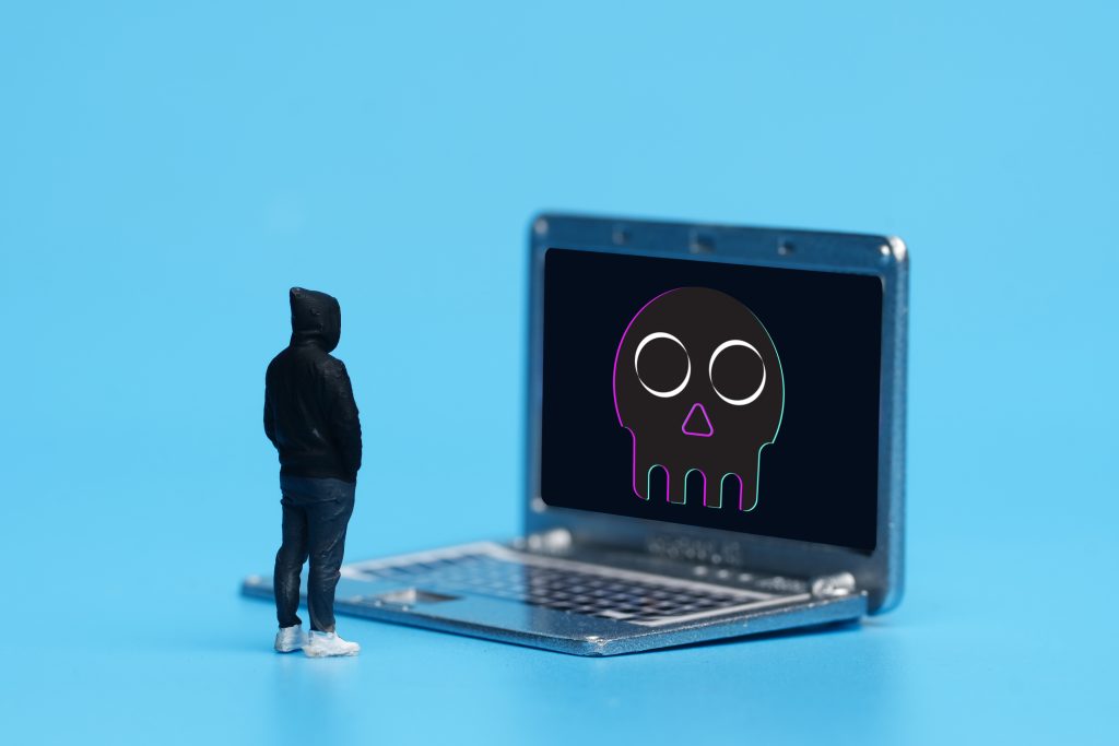 A picture of miniature with lapto insight and skull. Cyber security issue.